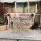 A wood Christmas Sign featuring Tiny Tim's quote "God Bless Us Everyone".  Scrooge and Tiny Tim stand  by a street lamp with snow falling. 